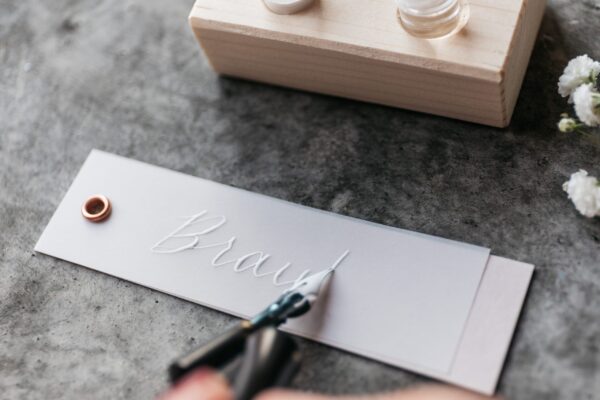 kalligrafierte Platzkarte und Anhänger für Gastgeschenke, weiße Tinte