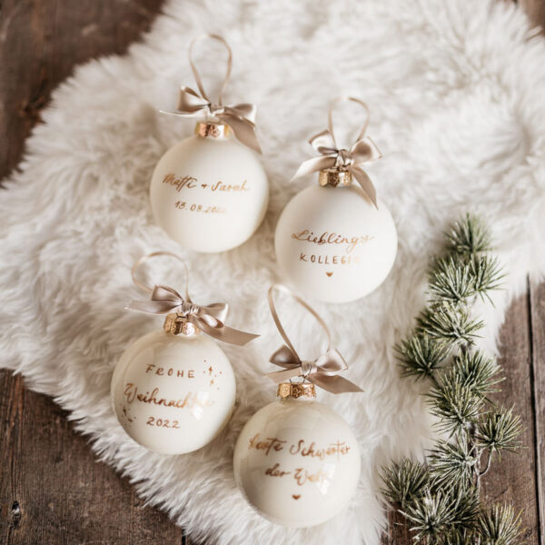 Vier personalisierte Weihnachtskugeln, die beschriftet sind.
